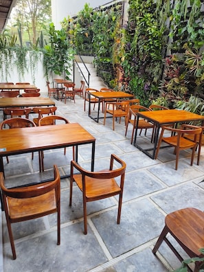 Un restaurant avec des tables et des chaises en bois, entouré de différentes sortes de plantes.