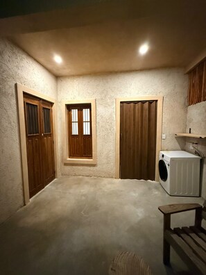 A laundry room with a washing machine, wooden cabinets, and a bench. - Las JULIAS Cuarto privado (Mérida)