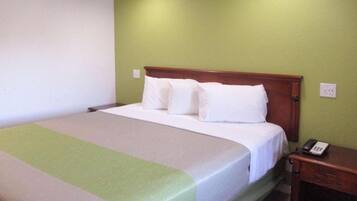 A single bed with a wooden headboard, white bedding, and a bedside table with a telephone.