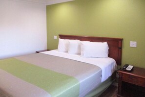 A single bed with a wooden headboard, white bedding, and a bedside table with a telephone.