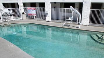 A swimming pool with a white fence, a lifeguard chair, and a caution sign.