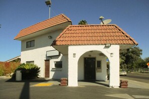 A two-story building with a red-tiled roof, a satellite dish, and a small entrance with an archway. - 1 King Bed | Non-Smoking, Micfridge (Fresno CA)