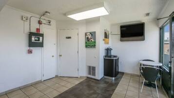 A hotel lobby with a reception desk, a trash bin, a microwave, and a TV mounted on the wall.