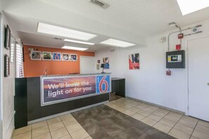 A hotel reception area with a counter, a sign indicating the number 6, and a tiled floor.