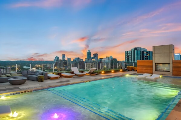 A rooftop pool with lounge chairs and a city skyline view at dusk. - Rooftop Pool + Skyline Views • Near Rainey Street + Downtown | Panoramic Summit (Austin)
