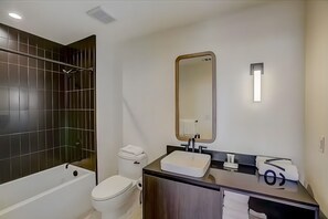 Ein modernes Badezimmer mit Badewanne, Toilette und Waschtisch mit Spiegel.