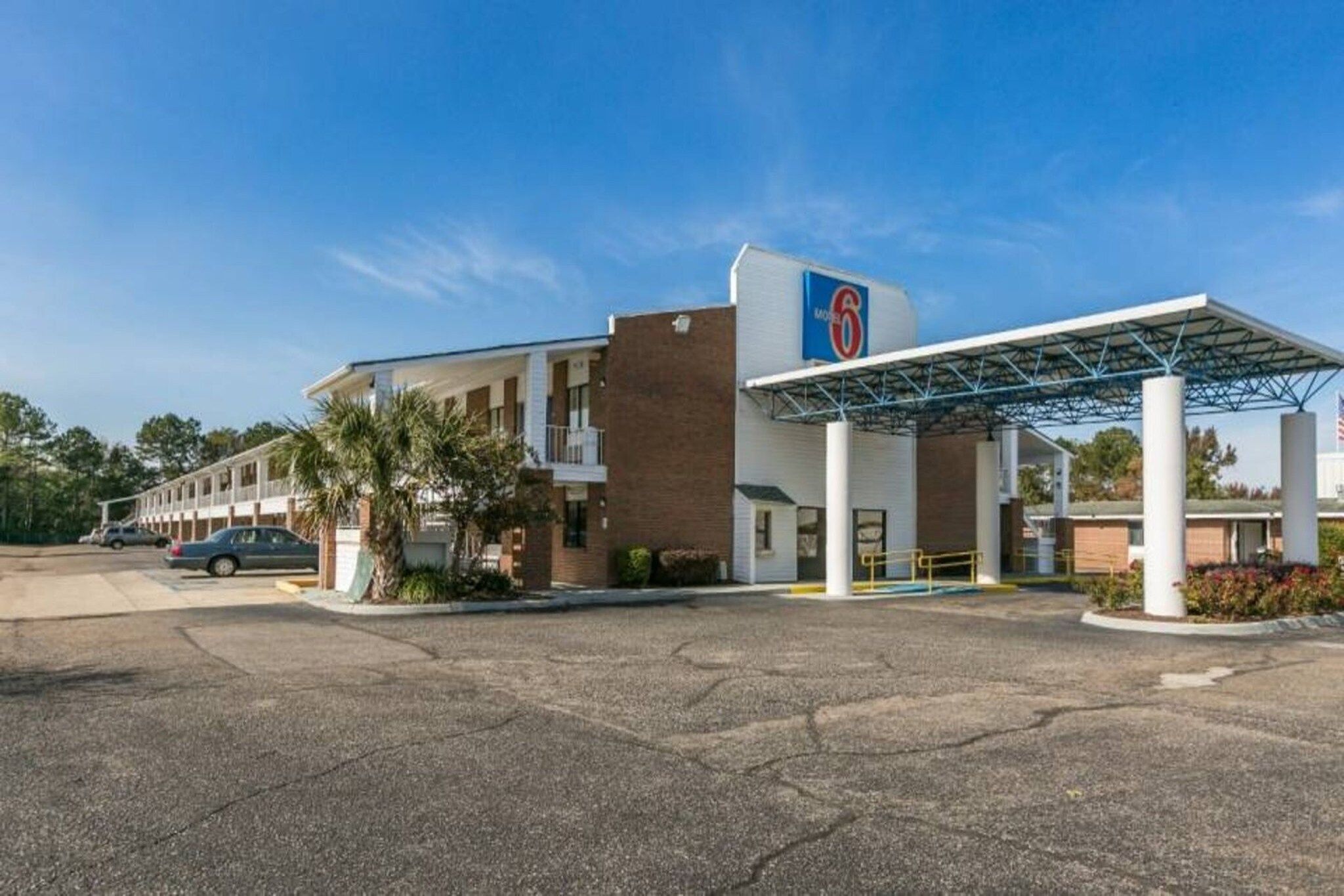 Un motel doté d’une station-service, d’un parking couvert et d’une rangée de chambres.