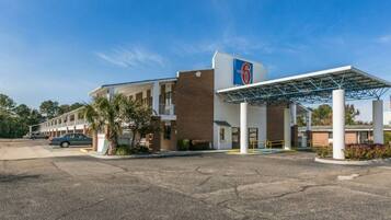 Un motel doté d’une station-service, d’un parking couvert et d’une rangée de chambres.
