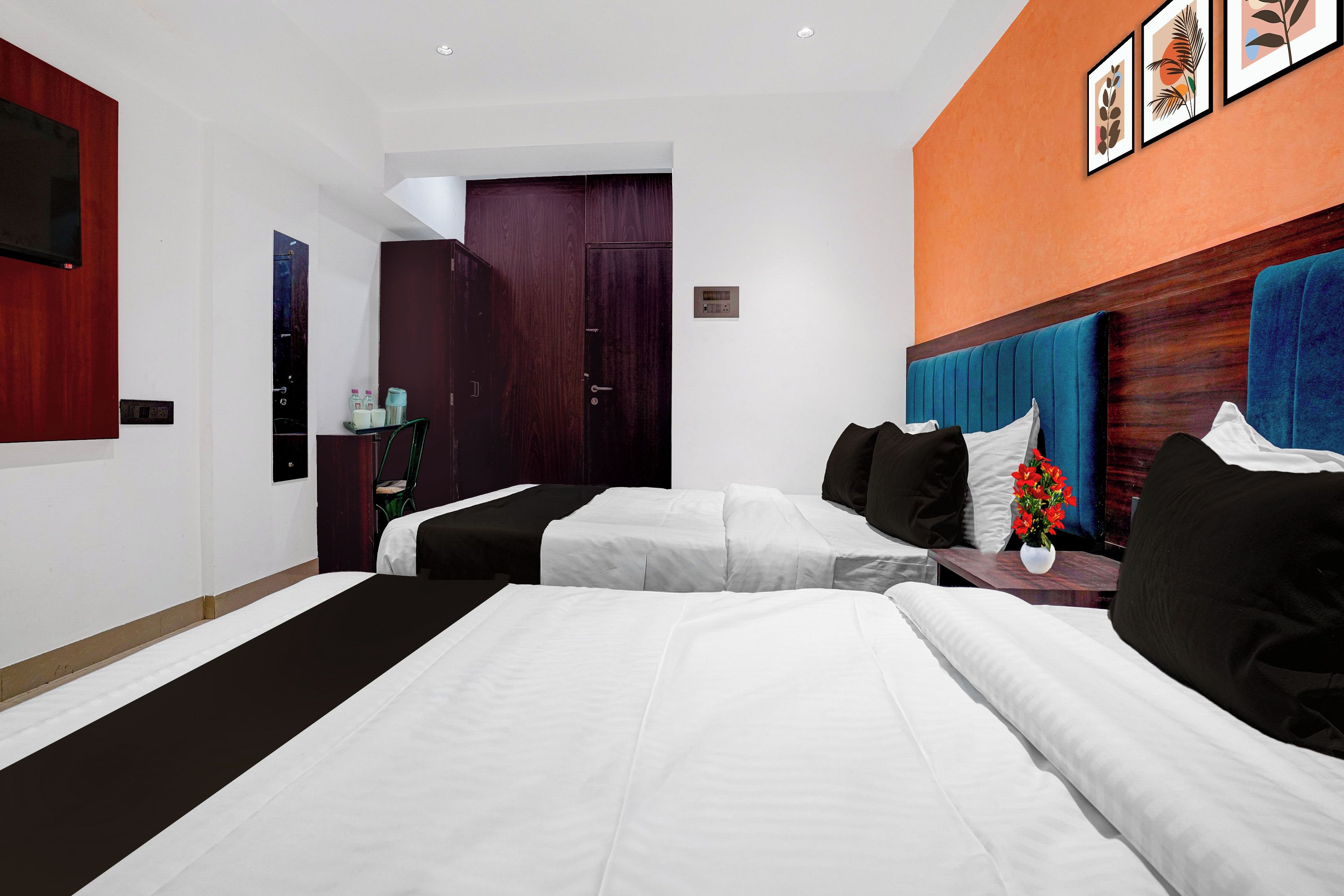 A hotel room with a large bed, a bedside table with a vase of flowers, and a wall-mounted TV.