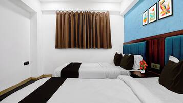 Una habitación de hotel con dos camas, una pared azul decorativa y una cortina.