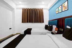 A hotel room with two beds, a blue accent wall, and a curtain. - Collection O Santacruz Railway Station (Mumbai)