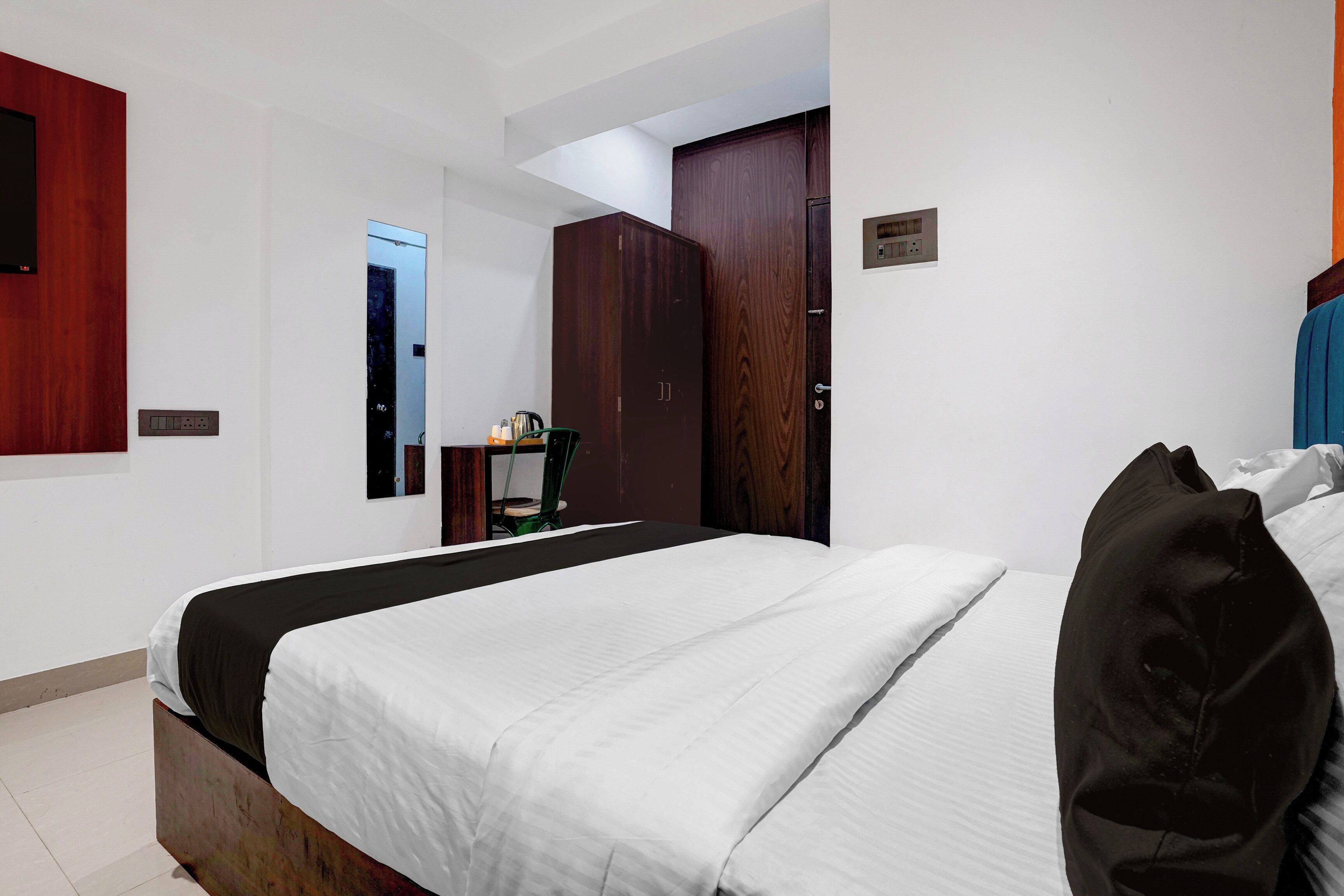 Habitación de hotel con cama, armario, espejo y una mesita con tetera.