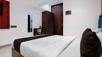 Habitación de hotel con cama, armario, espejo y una mesita con tetera.