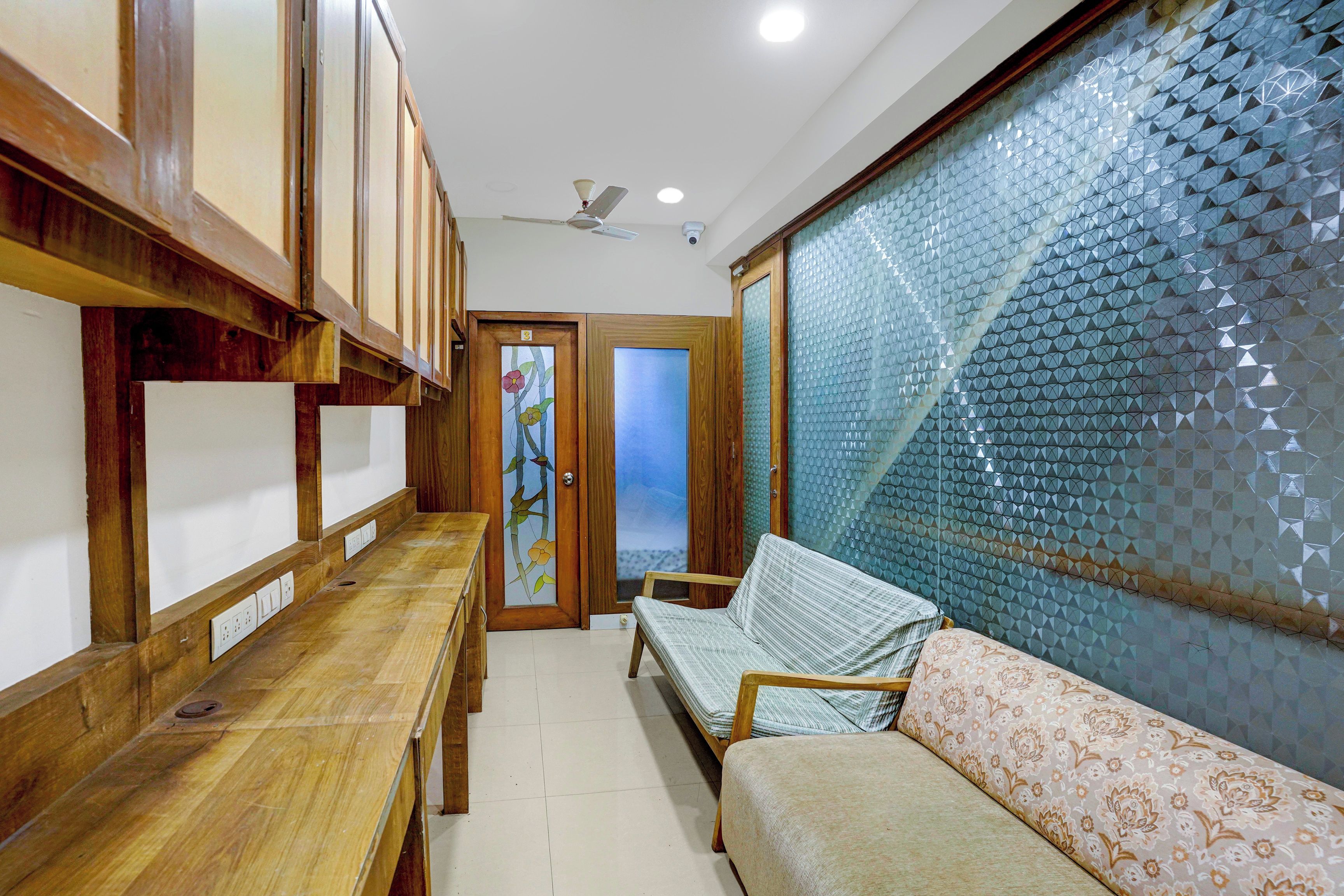 A hallway with a wooden bench, a sofa, and a door with a glass panel.