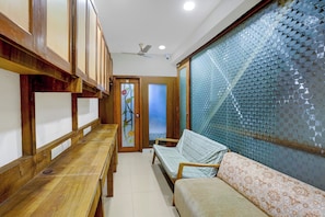 A hallway with a wooden bench, a sofa, and a door with a glass panel. - Collection O Santacruz Railway Station (Mumbai)