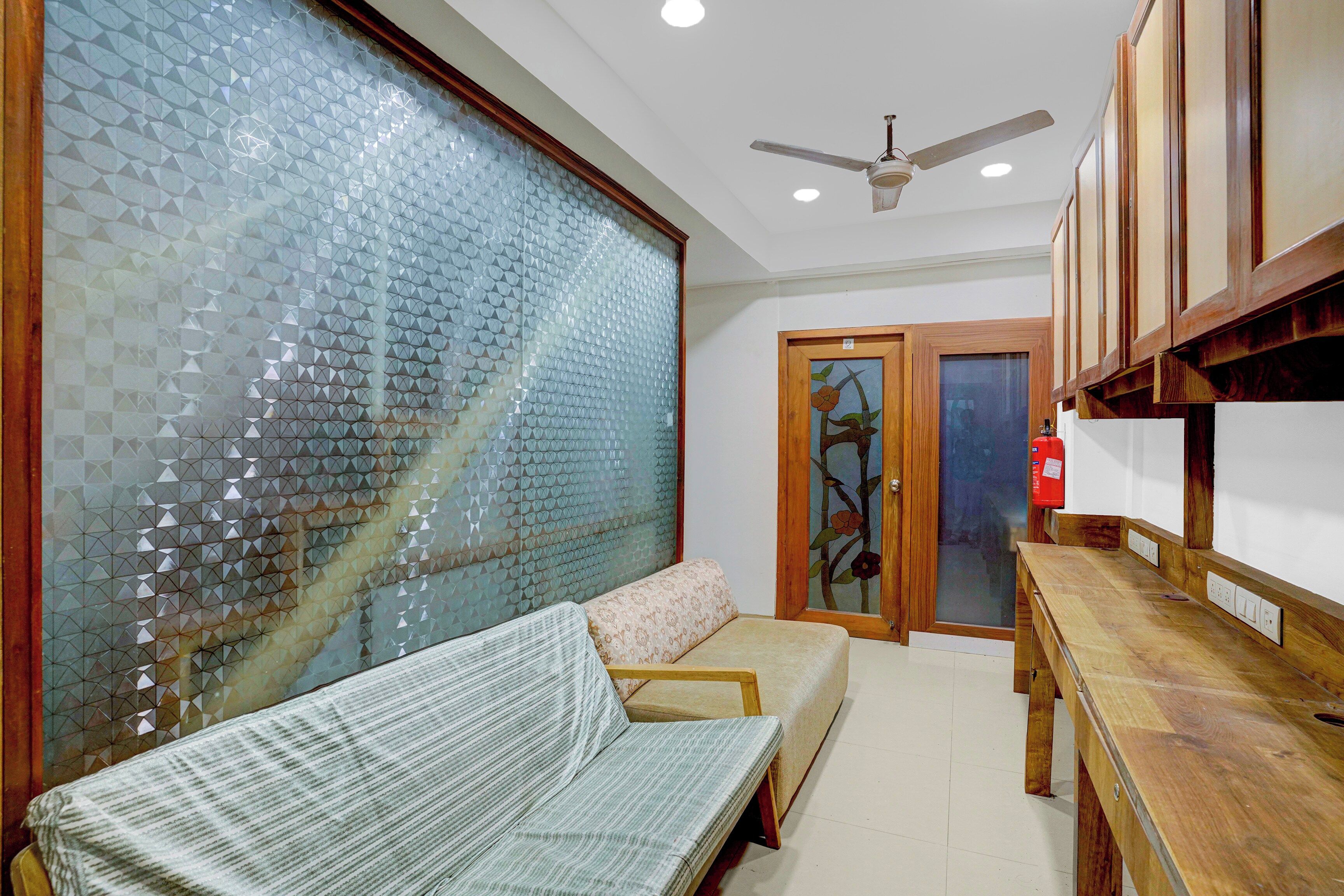 A room with a sofa, a wooden table, a ceiling fan, and a door with a floral design.