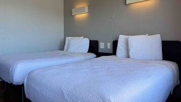 A hotel room with two beds, each with white bedding and headboards.