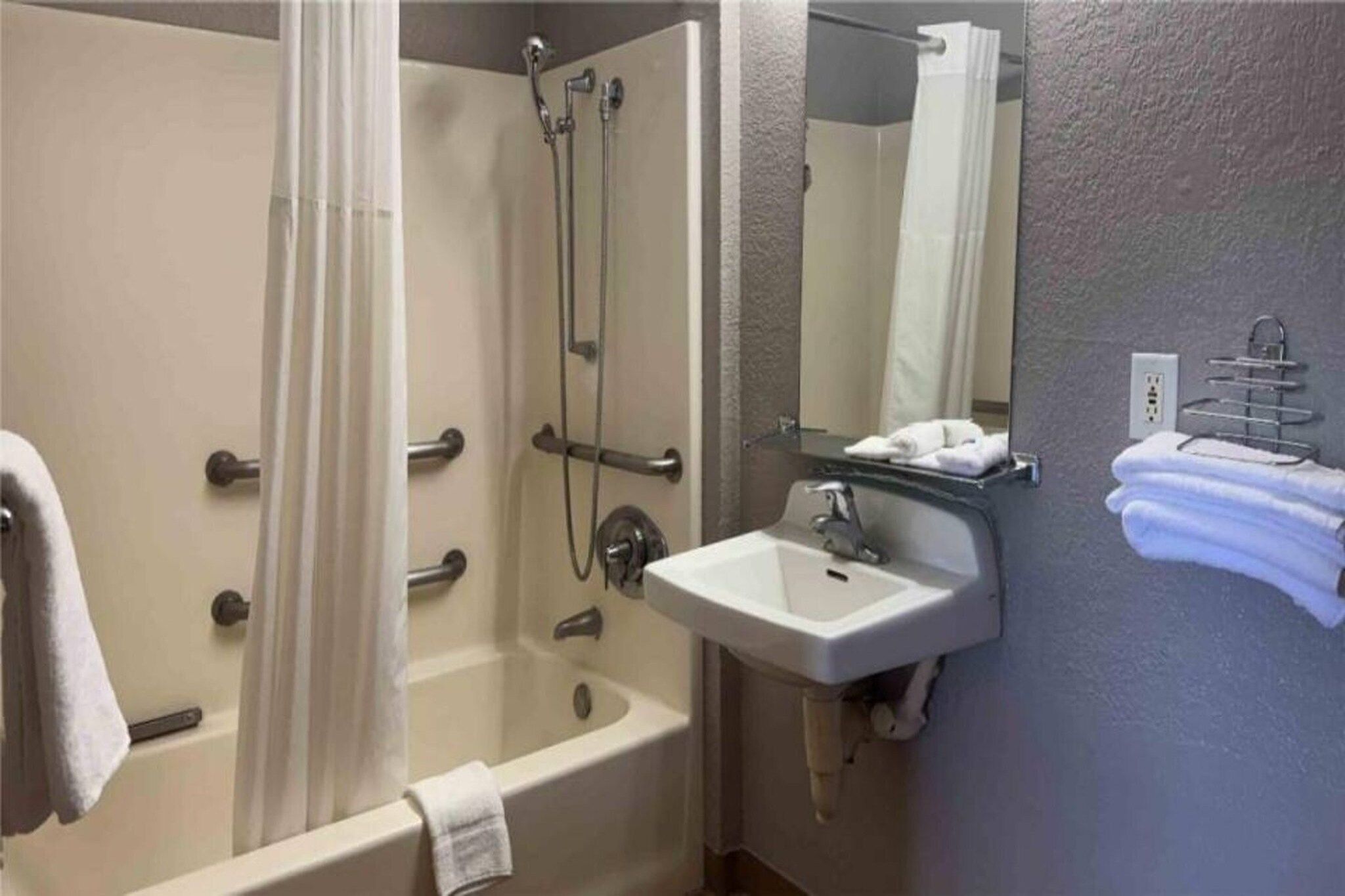 A bathroom with a bathtub, a shower, a sink, and a mirror.