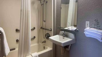 A bathroom with a bathtub, a shower, a sink, and a mirror.