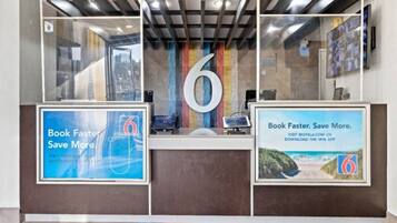 A reception desk with a large number '6' sign, two framed promotional posters, and a modern interior design.