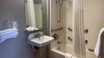 A bathroom with a sink, mirror, towel rack, and a shower area with a curtain.