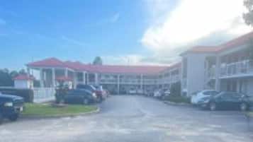 Un edificio con techo rojo, varios espacios de estacionamiento y cielo despejado.