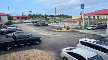 A parking lot with multiple cars, a gas station, and a building with a red roof.