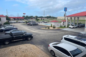 Un estacionamiento con varios autos, una gasolinera y un edificio con techo rojo.