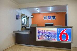 A hotel reception desk with a large sign reading 'We leave the light on for you.'