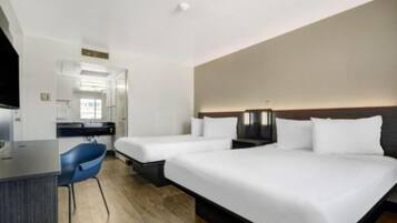 A hotel room with two beds, a desk, and a chair.