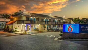 A motel with a prominent sign indicating it is number 6, featuring a modern design with multiple floors and a flat roof.