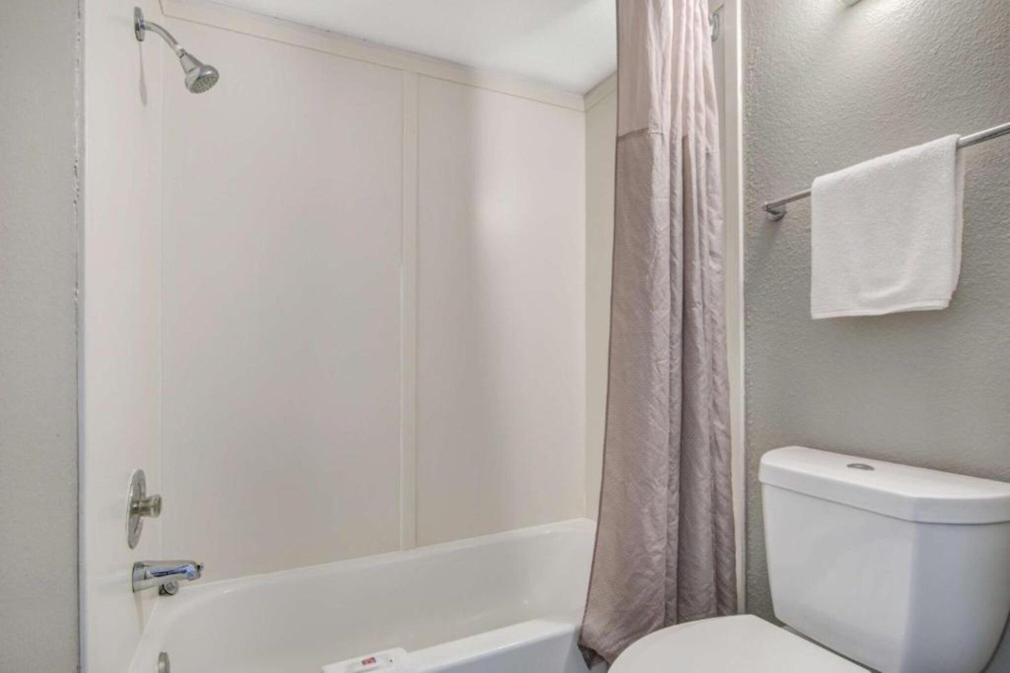 A bathroom with a bathtub, toilet, and shower curtain.