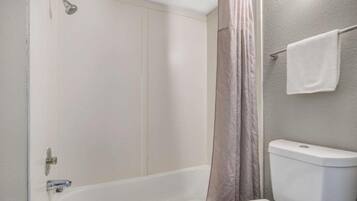 A bathroom with a bathtub, toilet, and shower curtain.