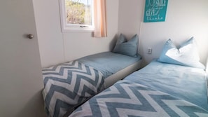 A bedroom with two beds, a window, and a wall sign. - DD 85 - Duindoorn Campground (IJmuiden)