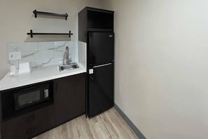 A compact kitchen with a built-in microwave, a sink, and a black refrigerator.