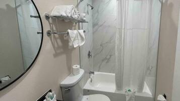 A bathroom with a toilet, sink, and bathtub. There is a towel rack with towels and a shower curtain.