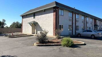 A building with a flat roof, a small entrance, and a parking lot with a few cars.