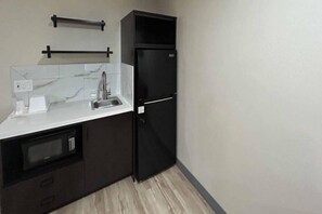 A compact kitchen with a built-in microwave, a sink, and a black refrigerator. - 1 Queen Bed | ADA/RI Shower/Nsmk/Kitchen (Cameron Park)