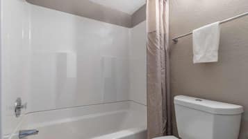 A bathroom with a bathtub, toilet, and shower curtain.