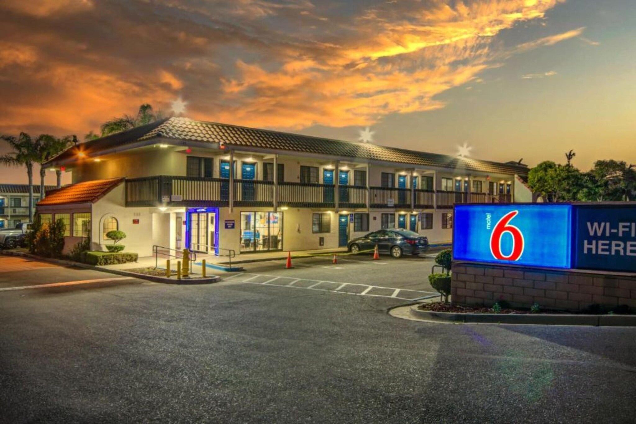 A motel with a prominent sign indicating it is number 6, featuring a modern design with multiple floors and a flat roof.