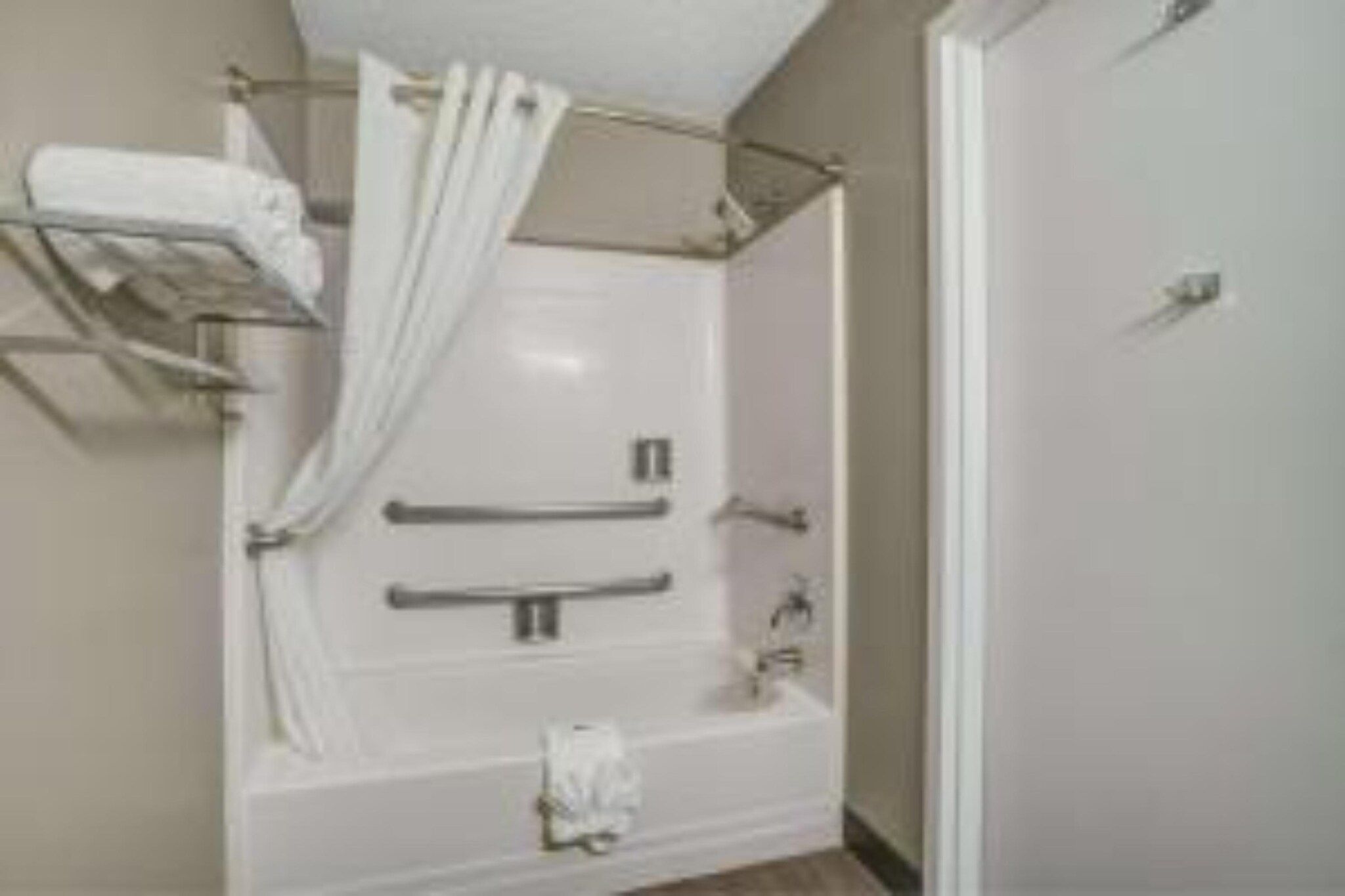 A bathroom with a bathtub, a shower, a towel rack, and a toilet.