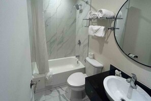 A bathroom with a bathtub, toilet, and sink.