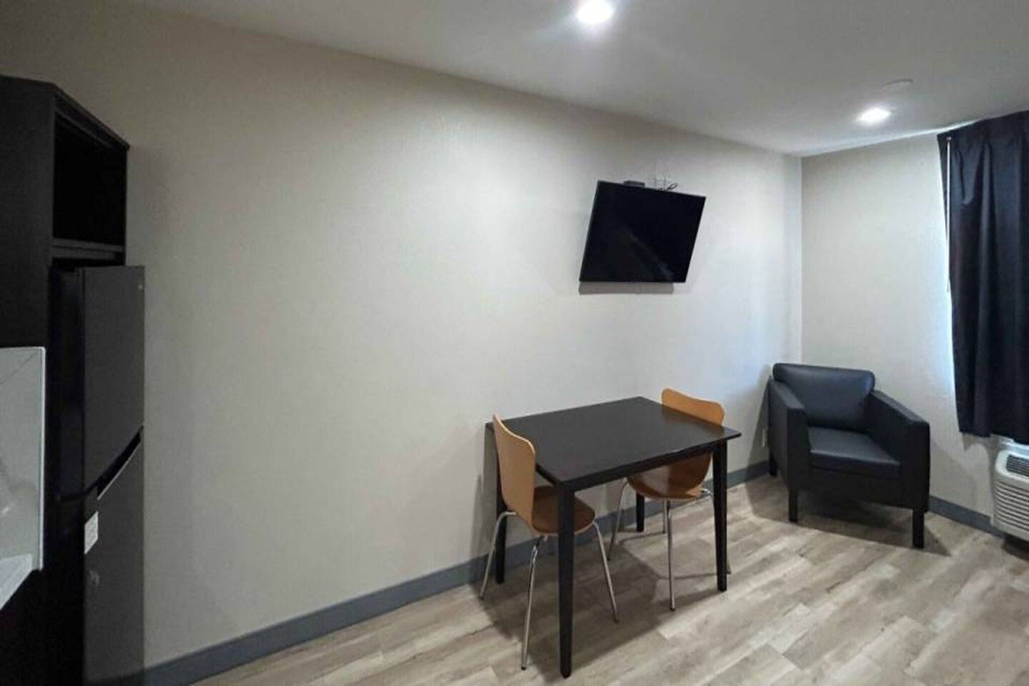 A small room with a table and two chairs, a television mounted on the wall, and a couch.