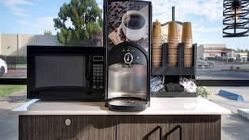 Une machine à café avec une tasse à café et des grains de café exposés.