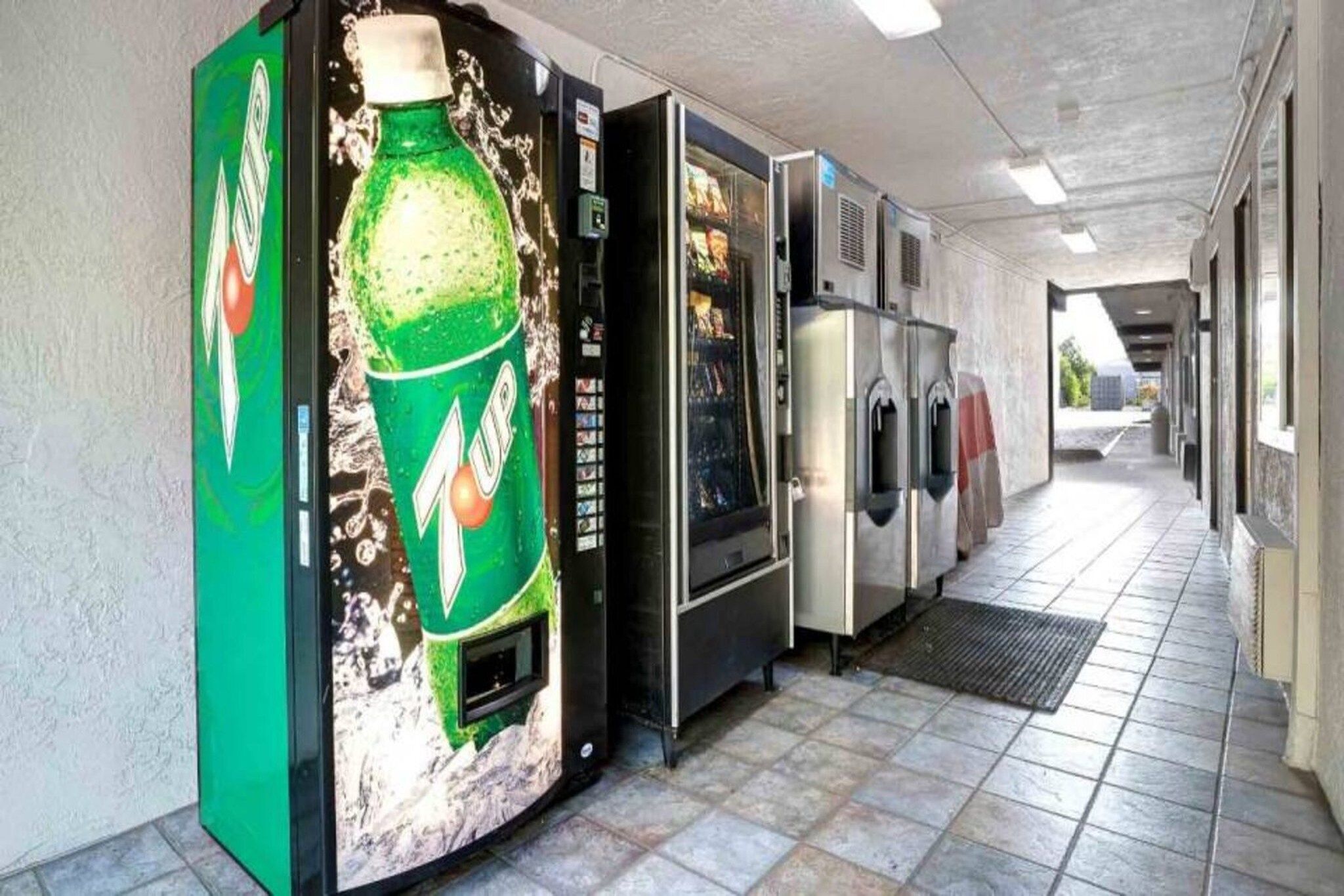 A corridor with vending machines, including a 7UP cooler and a refrigerator.