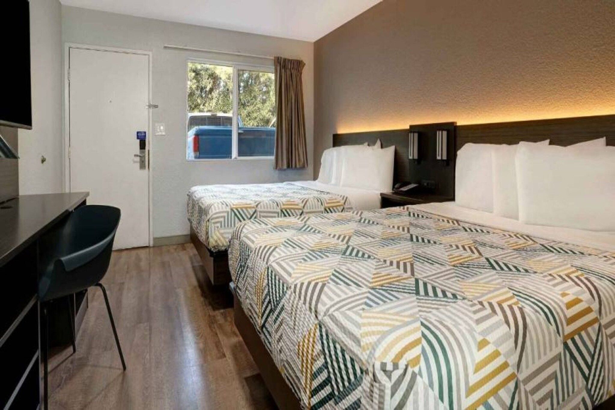 A hotel room with two beds, a desk, and a television.