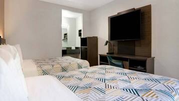 Une chambre d’hôtel avec deux lits, un bureau, une télévision et un miroir.