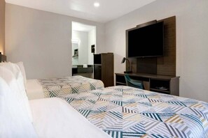 Een hotelkamer met twee bedden, een bureau, een televisie en een spiegel.
