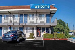 A two-story motel with a 'Welcome' sign, a parking lot, and a 'No Parking Fire Lane' sign. - 1 Full Bed | ADA/RI Shower/Mini Fridge (Rancho Cordova)