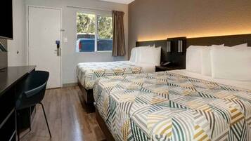 A hotel room with two beds, a desk, and a television.